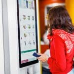 woman ordering at digital kiosk in restaurant