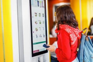 woman ordering at digital kiosk in restaurant