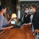 two people checking into hotel with facemasks