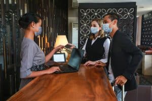 two people checking into hotel with facemasks